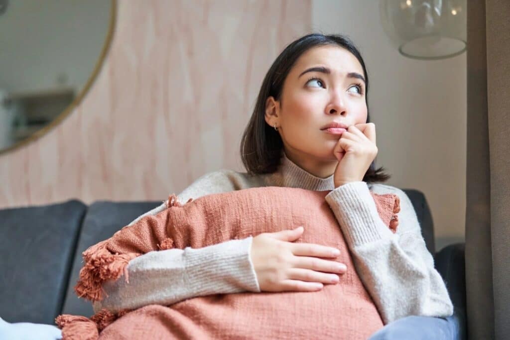 woman looking pensive and deep in thinking while sitting in the living room