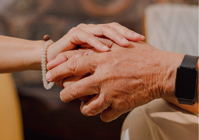 Close-up of two people holding hands in a supportive and reassuring gesture