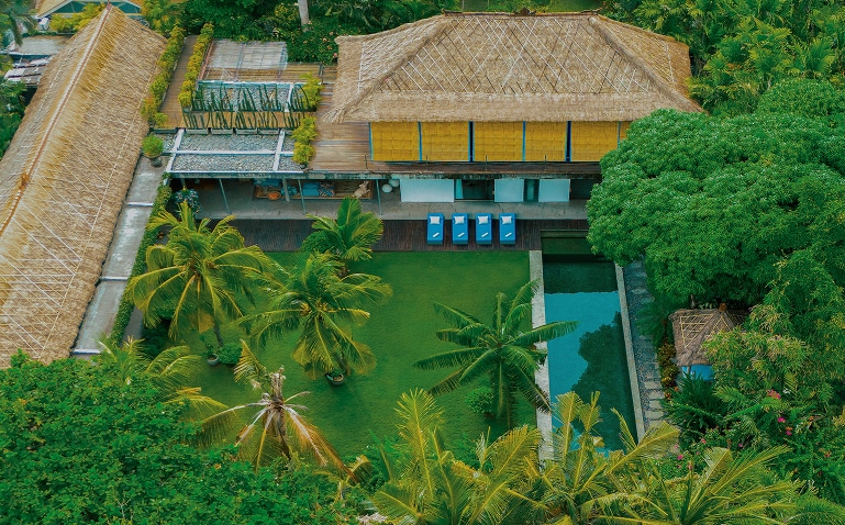 Aerial view of The Place Retreats in Bali, with thatched-roof buildings, tropical gardens and a swimming pool