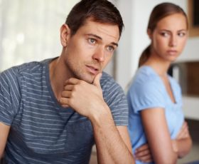 man looking distracted while wife is looking angry in the background