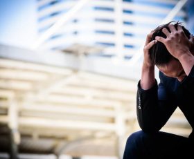 man looking stressed, head down, while outdoors
